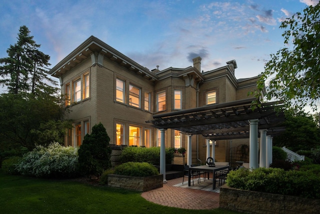 226 Grotto St S, Saint Paul, MN 55105 - back of house at dusk with a pergola, a patio, a lawn, and brick siding