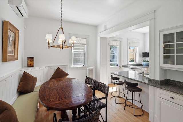 226 Grotto St S, Saint Paul, MN 55105 - dining area featuring an AC wall unit, radiator heating unit, a chandelier, and light wood finished floors