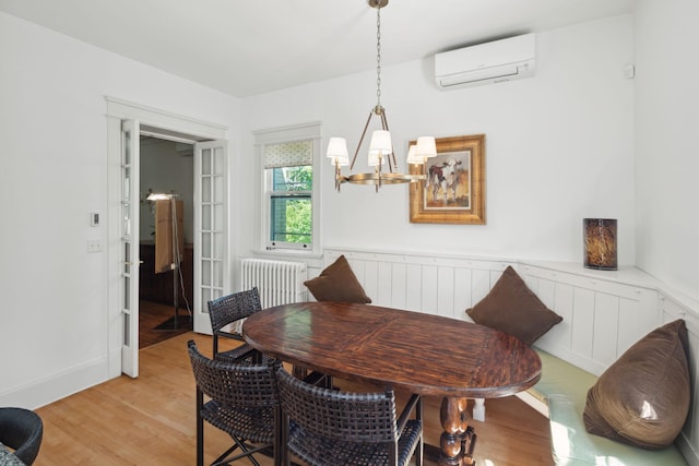 226 Grotto St S, Saint Paul, MN 55105 - dining space featuring a wall unit AC, radiator heating unit, a chandelier, light wood finished floors, and a wainscoted wall