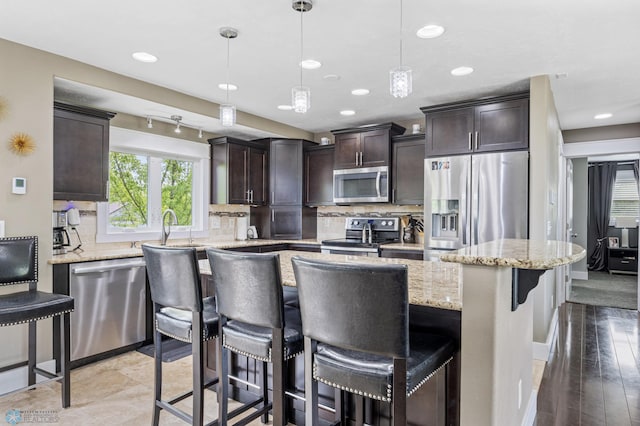 18117 Cherry Creek Ln, Erie Twp, MN 56501 - kitchen featuring appliances with stainless steel finishes, a kitchen island, dark brown cabinets, tasteful backsplash, and light stone counters