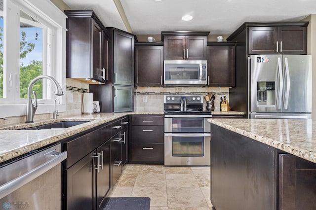18117 Cherry Creek Ln, Erie Twp, MN 56501 - kitchen with stainless steel appliances, a sink, decorative backsplash, light stone countertops, and dark brown cabinets