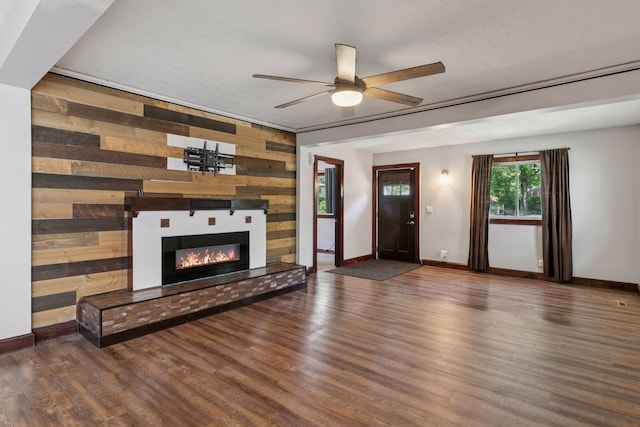 1148 Geranium Ave E, Saint Paul, MN 55106 - unfurnished living room featuring ceiling fan, baseboards, wood walls, and a glass covered fireplace