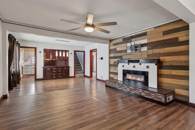1148 Geranium Ave E, Saint Paul, MN 55106 - unfurnished living room featuring wood walls, a ceiling fan, a tiled fireplace, stairs, and wood finished floors