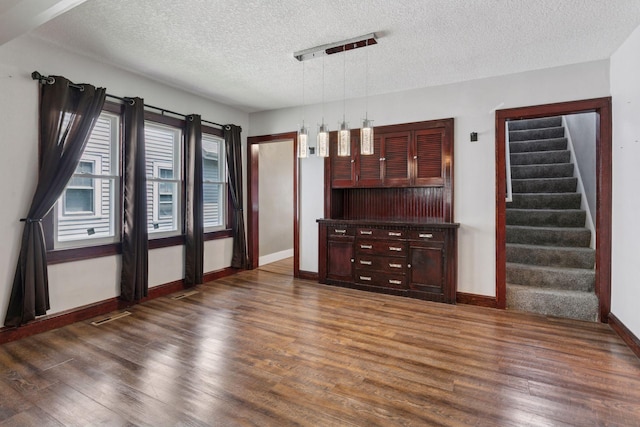 1148 Geranium Ave E, Saint Paul, MN 55106 - unfurnished living room featuring dark wood finished floors, baseboards, a textured ceiling, and stairs