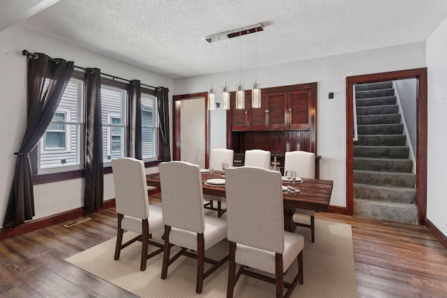 1148 Geranium Ave E, Saint Paul, MN 55106 - dining room featuring baseboards, wood finished floors, a textured ceiling, and stairs