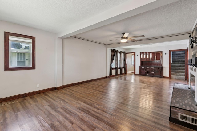1148 Geranium Ave E, Saint Paul, MN 55106 - unfurnished living room with wood finished floors, ceiling fan, a textured ceiling, baseboards, and stairway