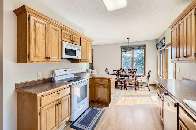 1110 Lia Ct, Northfield, MN 55057 - kitchen featuring white appliances, light wood-type flooring, a textured ceiling, hanging light fixtures, and a peninsula