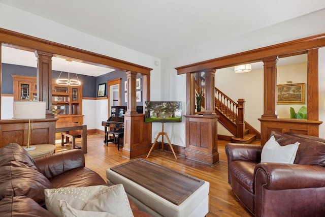 896 Carroll Ave, Saint Paul, MN 55104 - living area featuring decorative columns, wood finished floors, stairs, and a chandelier