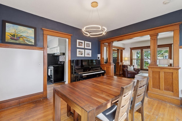 896 Carroll Ave, Saint Paul, MN 55104 - dining room featuring ornate columns, light wood-style floors, and a chandelier