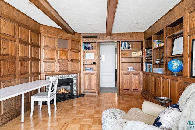 2900 London Rd, Duluth, MN 55804 - living room featuring wood walls, beamed ceiling, a textured ceiling, and a fireplace with flush hearth