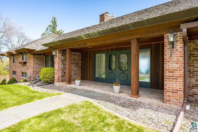 2900 London Rd, Duluth, MN 55804 - property entrance with a chimney, brick siding, a porch, and a yard