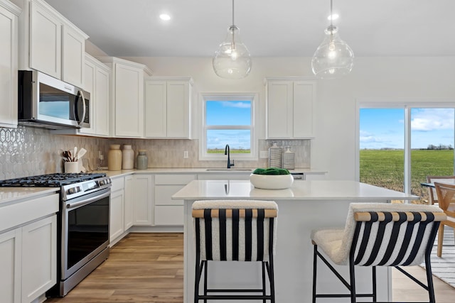 252 6th St NW, Delano, MN 55328 - kitchen with stainless steel appliances, a sink, a center island, a kitchen bar, and light countertops