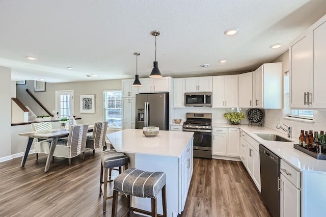 21749 Lilac Dr, Farmington, MN 55024 - kitchen with appliances with stainless steel finishes, a sink, a kitchen breakfast bar, dark wood-style flooring, and a center island