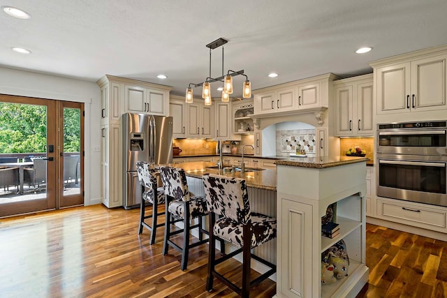 21570 France Blvd, Credit River Twp, MN 55044 - kitchen featuring stainless steel appliances, cream cabinets, open shelves, a breakfast bar, and recessed lighting