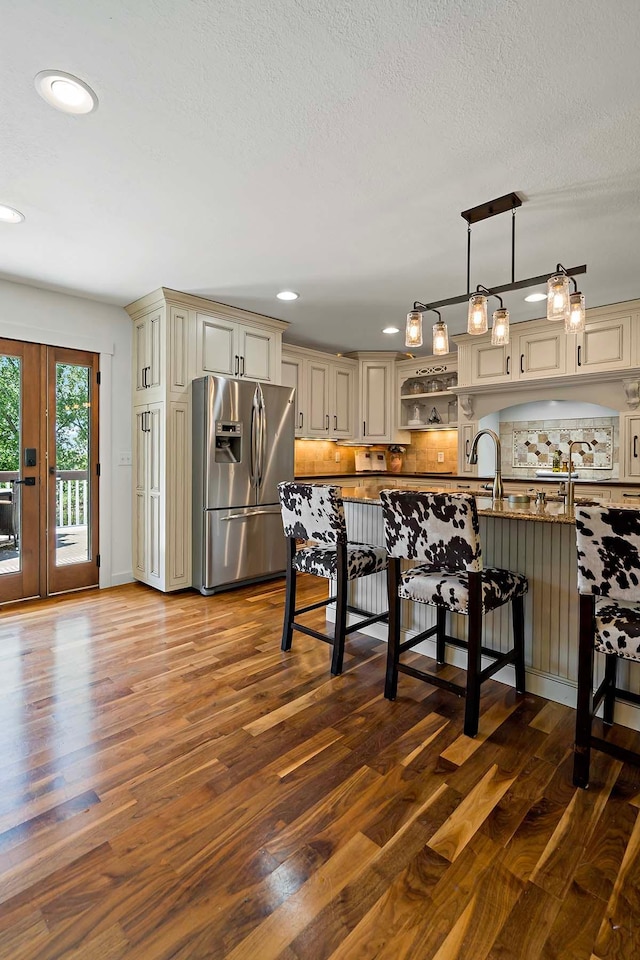 21570 France Blvd, Credit River Twp, MN 55044 - kitchen with stainless steel refrigerator with ice dispenser, cream cabinetry, dark wood-style flooring, backsplash, and a textured ceiling