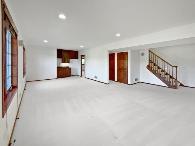 1101 Golfers Ct SE, Rochester, MN 55904 - unfurnished living room featuring recessed lighting, light carpet, stairway, and baseboards