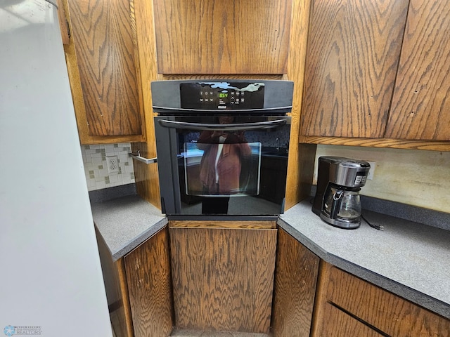 103 4th St S, Fairmount, ND 58030 - kitchen featuring oven, backsplash, freestanding refrigerator, and brown cabinetry