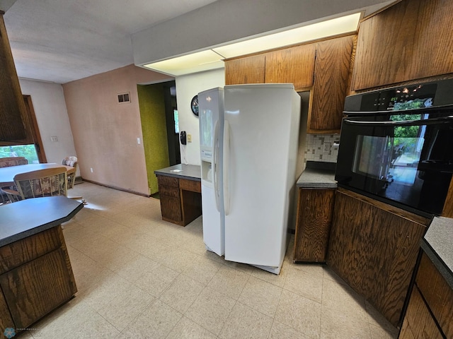 103 4th St S, Fairmount, ND 58030 - kitchen featuring white fridge with ice dispenser, black oven, light floors, tasteful backsplash, and dark countertops