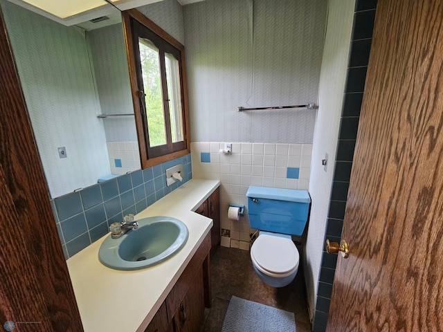 103 4th St S, Fairmount, ND 58030 - bathroom featuring toilet, vanity, tile walls, a wainscoted wall, and wallpapered walls