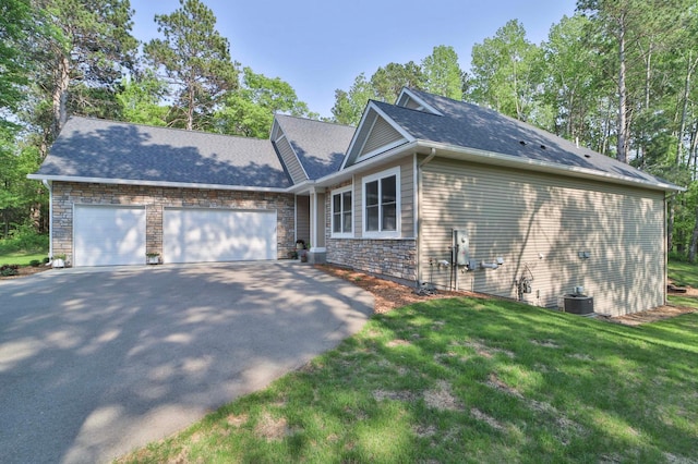 23904 Summer Haven Ln, Nisswa, MN 56468 - view of property exterior with asphalt driveway, an attached garage, a yard, cooling unit, and stone siding