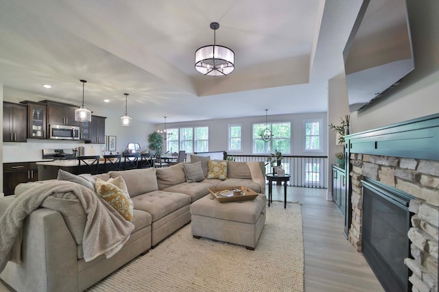 23904 Summer Haven Ln, Nisswa, MN 56468 - living area featuring light wood-style floors, a fireplace, recessed lighting, a raised ceiling, and a chandelier