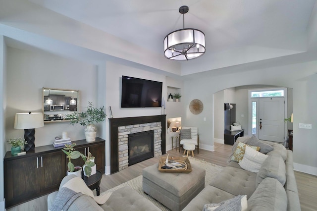 23904 Summer Haven Ln, Nisswa, MN 56468 - living room featuring arched walkways, a raised ceiling, wood finished floors, and baseboards