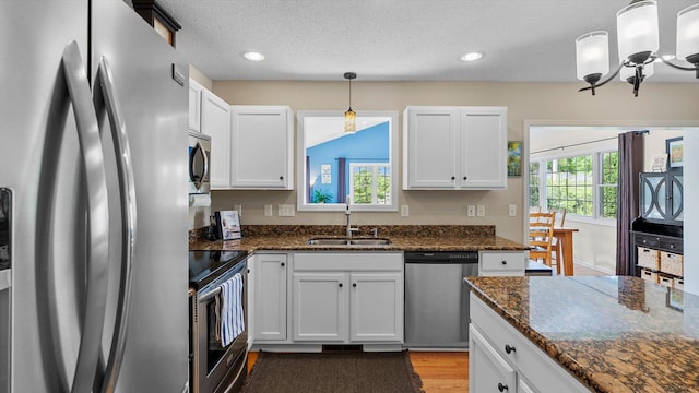 8548 139th St, Savage, MN 55378 - kitchen with appliances with stainless steel finishes, a sink, a chandelier, light wood-style floors, and white cabinets