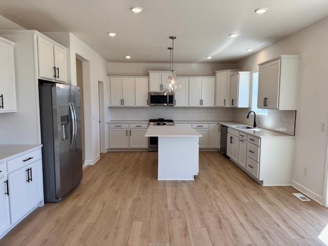 11325 Ithaca Ln N, Dayton, MN 55369 - kitchen featuring stainless steel appliances, a sink, light wood-style flooring, light countertops, and a center island