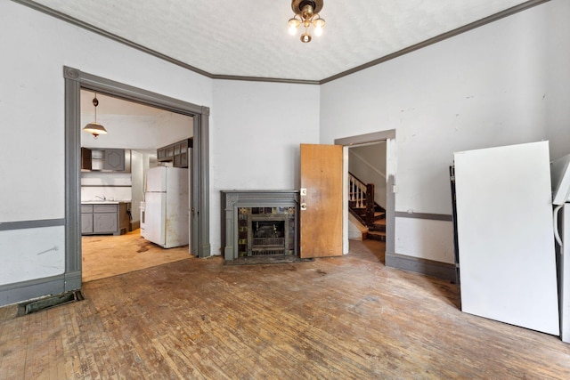 691 Burr St, Saint Paul, MN 55130 - unfurnished living room featuring ornamental molding, stairway, a fireplace, wood finished floors, and a sink