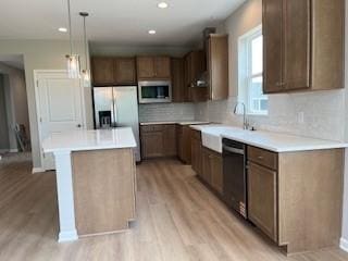 10051 Mulberry Ln, Corcoran, MN 55374 - kitchen with appliances with stainless steel finishes, light wood finished floors, a center island, tasteful backsplash, and recessed lighting