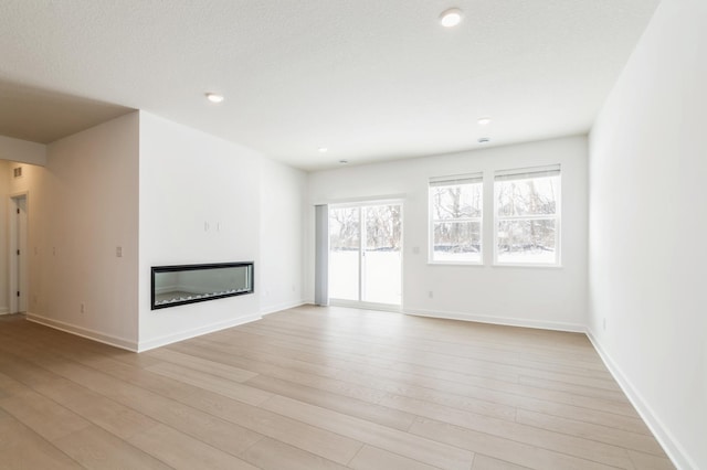 22615 Isla Way, Rogers, MN 55374 - unfurnished living room with a glass covered fireplace, light wood-style flooring, baseboards, and recessed lighting