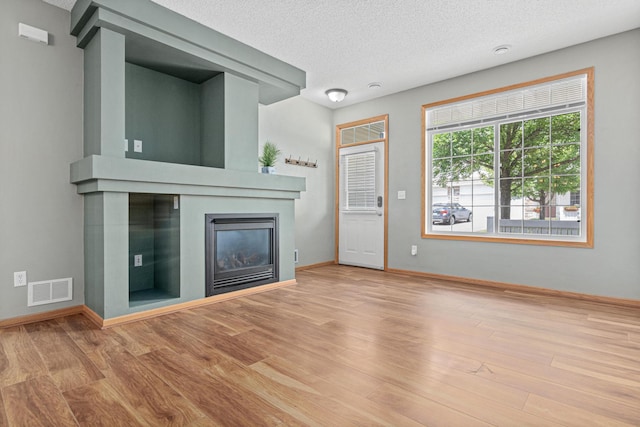 4707 Blaine Ave Unit 709, Inver Grove Heights, MN 55076 - unfurnished living room with a glass covered fireplace, wood finished floors, baseboards, and a textured ceiling