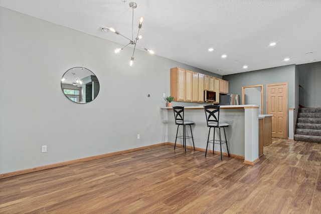 4707 Blaine Ave Unit 709, Inver Grove Heights, MN 55076 - kitchen featuring stainless steel appliances, light brown cabinetry, wood finished floors, a peninsula, and a breakfast bar