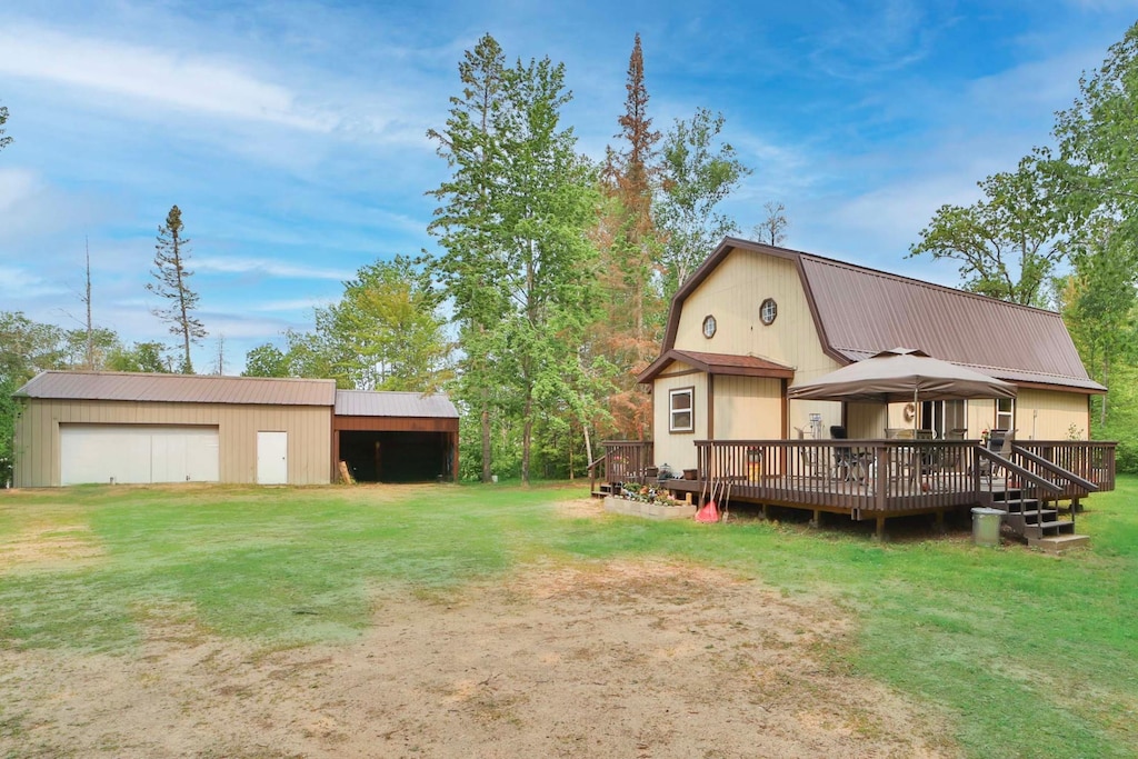 2155 County Road 55 NE, Remer, MN 56672 - rear view of house with a lawn, a gambrel roof, a detached garage, a wooden deck, and an outdoor structure