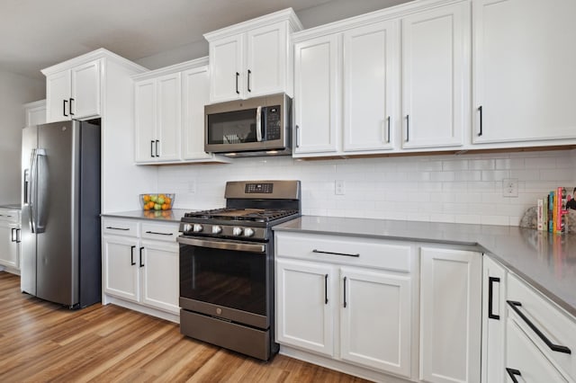 5282 Randolph Ave NE, Otsego, MN 55374 - kitchen with appliances with stainless steel finishes, white cabinetry, light wood finished floors, and decorative backsplash