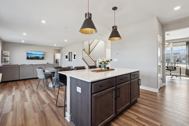 5282 Randolph Ave NE, Otsego, MN 55374 - kitchen featuring wood finished floors, a breakfast bar, light countertops, dark brown cabinetry, and a kitchen island