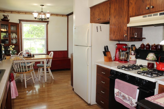 44500 Elmcrest Ave, Fish Lake Twp, MN 55032 - kitchen with gas stove, under cabinet range hood, light countertops, light wood-style flooring, and a chandelier
