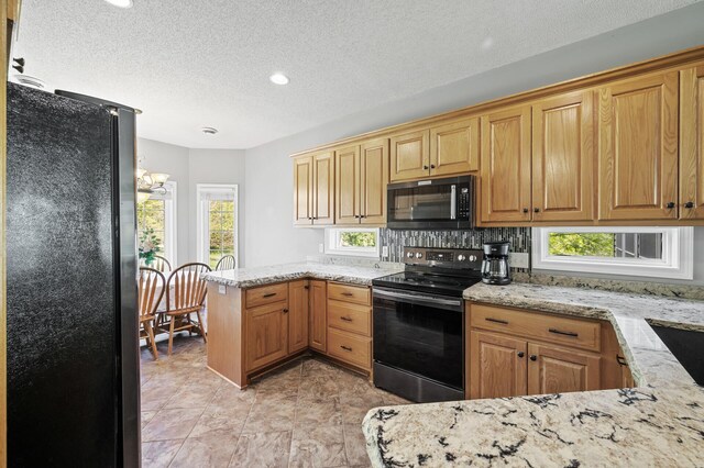 17260 Keystone Ave N, Hugo, MN 55038 - kitchen with black appliances, a peninsula, light stone counters, a textured ceiling, and backsplash