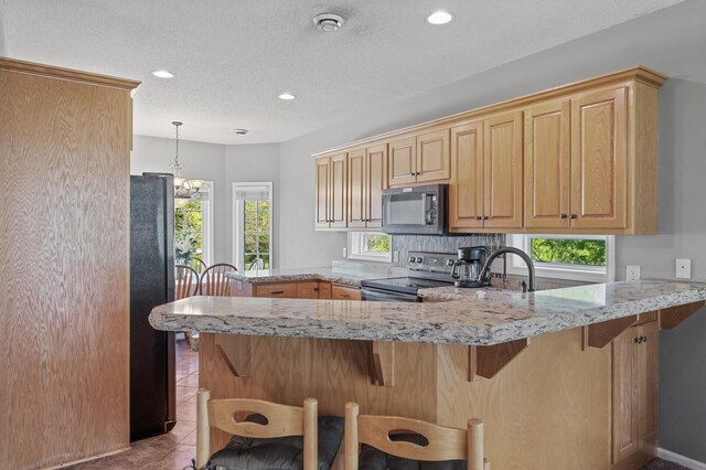 17260 Keystone Ave N, Hugo, MN 55038 - kitchen with electric stove, freestanding refrigerator, a peninsula, light stone counters, and recessed lighting