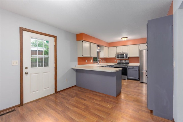 106 1/2 N St, Hudson, WI 54016 - kitchen featuring stainless steel appliances, a peninsula, wood finished floors, and light countertops