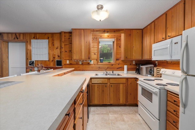 106 1/2 N St, Hudson, WI 54016 - kitchen featuring white appliances, a sink, light countertops, wood walls, and brown cabinetry