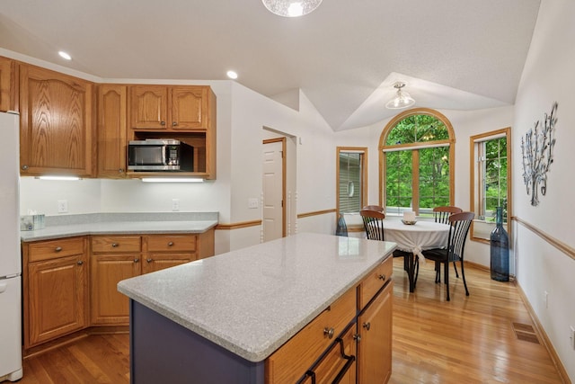 11202 Virginia Rd, Bloomington, MN 55438 - kitchen featuring stainless steel microwave, light countertops, light wood-style flooring, vaulted ceiling, and freestanding refrigerator