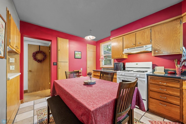 1413 11th Ave S, Fargo, ND 58103 - kitchen with white gas range oven, under cabinet range hood, light tile patterned floors, and dark countertops