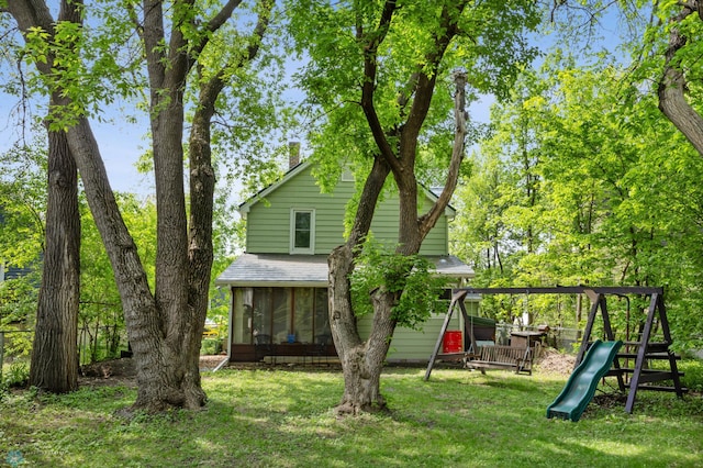 1413 11th Ave S, Fargo, ND 58103 - rear view of property with a playground, a sunroom, a lawn, and roof with shingles