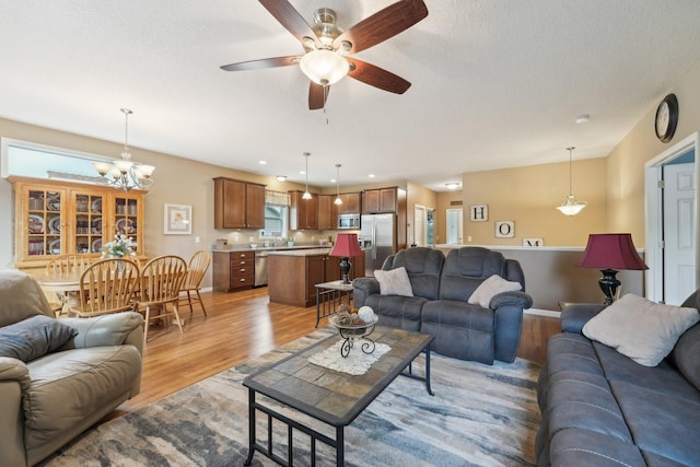 3157 Doneene Ln, Eagan, MN 55121 - living room featuring light wood-style floors, ceiling fan, a chandelier, baseboards, and a textured ceiling