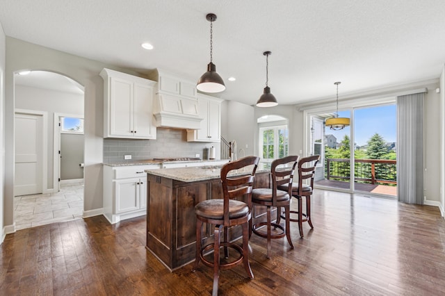 6005 Comstock Ln N, Plymouth, MN 55446 - kitchen featuring arched walkways, dark wood-style flooring, decorative backsplash, white cabinetry, and recessed lighting
