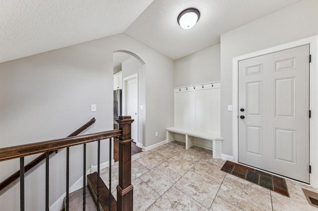 6005 Comstock Ln N, Plymouth, MN 55446 - mudroom with arched walkways, a textured ceiling, lofted ceiling, light tile patterned floors, and baseboards