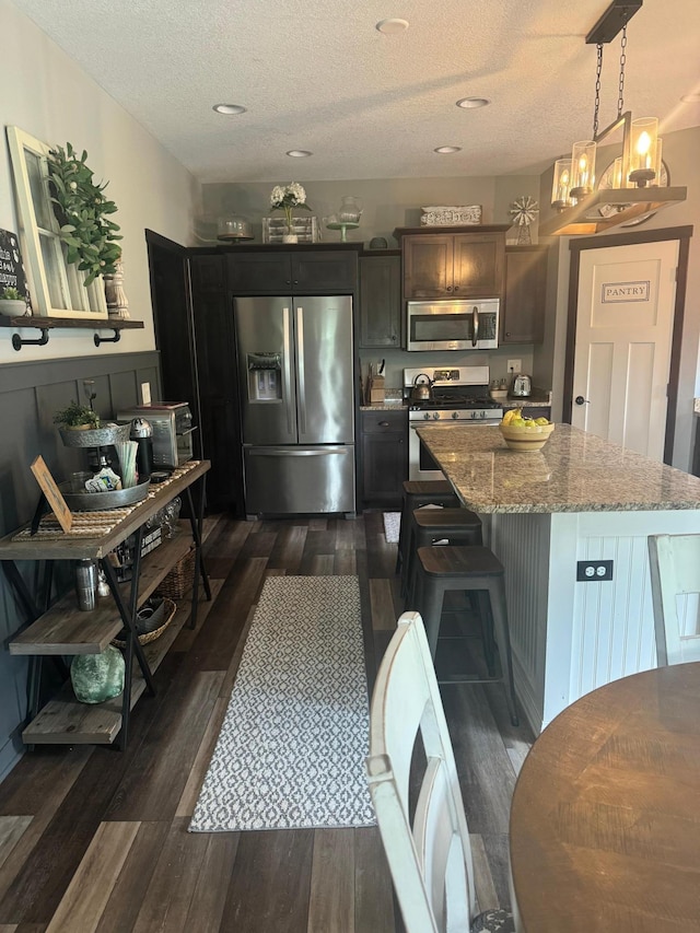 22592 43rd Ave, Saint Augusta, MN 56301 - kitchen featuring appliances with stainless steel finishes, dark wood finished floors, a center island, light stone counters, and a textured ceiling