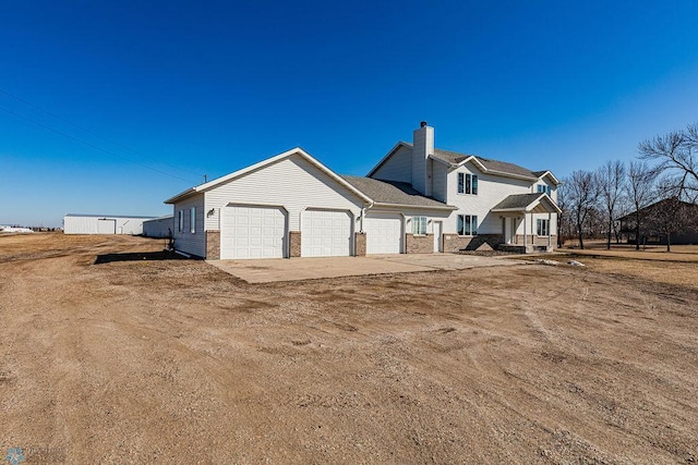 2717 88th Ave S, Fargo, ND 58104 - back of house with an attached garage, concrete driveway, a chimney, and brick siding