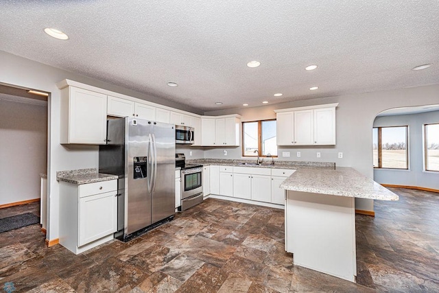2717 88th Ave S, Fargo, ND 58104 - kitchen with stainless steel appliances, a peninsula, a sink, a textured ceiling, and white cabinets
